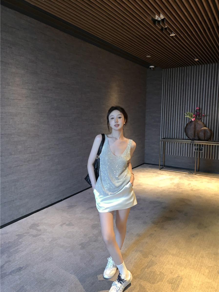 Real shot of a hot girl covered in rhinestones and wearing a ladylike knitted camisole and short skirt suit